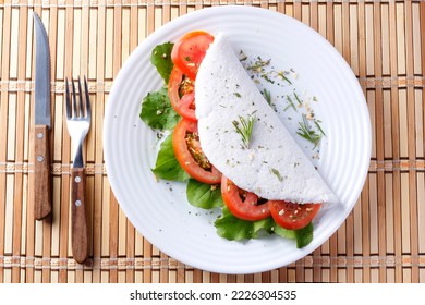 tapioca or beiju with vegetables, tomato, arugula, in white plate over rustic wooden table. Vegan, fitness food, gluten free. top view - Shutterstock ID 2226304535