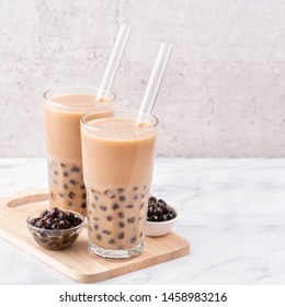 Tapioca Pearl Ball Bubble Milk Tea, Popular Taiwan Drink, In Drinking Glass With Straw On Marble White Table And Wooden Tray, Close Up, Copy Space.