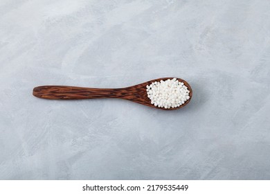 Tapioca Pearl In Ebony Wooden Spoon On Grey Background, Top View. White Sago Pearls. Tapioca Ball Used In Culinary.