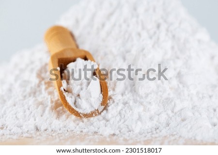 Tapioca starch or flour powder. White powdered tapioca starch in a wooden scoop, dry cassava root.