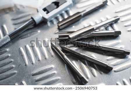 Tapped Hole or Threaded Hole tools on Diamond metal plate ,screw hand tap cutting tool. tap and drill bit making hole.selective focus 
