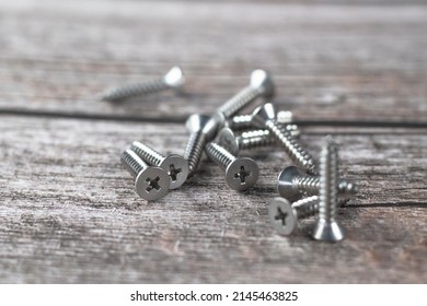Tapping screws made of steel on wood background, metal screw, iron screw, chrome screw, screws as a background, wood screw, concept industry. copy space for text.