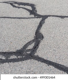 Tar Patching Cracks In Asphalt Pavement. Focus Is On The Tar In At The Bottom.