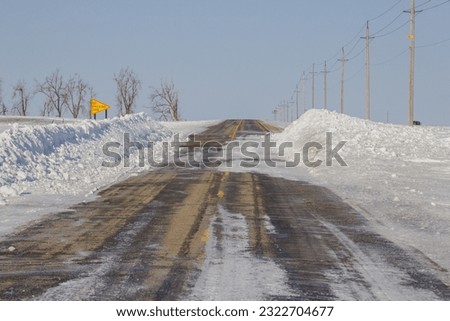 Tar road lined with deep snow drifts.