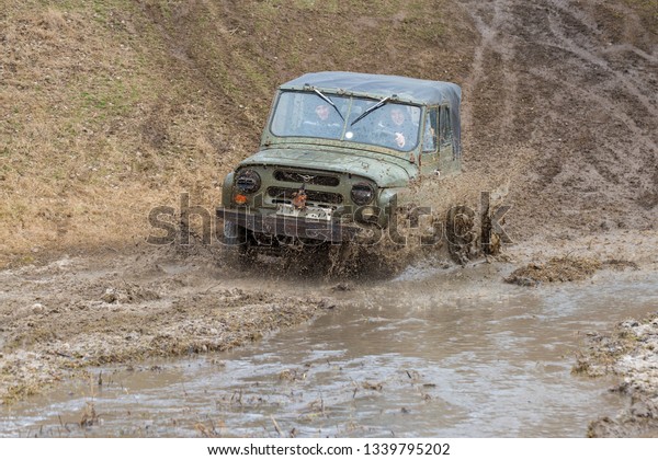 Taraclia, Moldova - 23. 02. 2019: Rally on Russian SUVs\
in the mud in winter, Trapped all-terrain vehicle pulled out of the\
river    