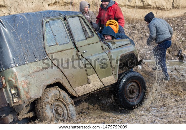 Taraclia, Moldova - 23. 02. 2019: Rally on Russian\
SUVs in the mud in winter, Trapped all-terrain vehicle pulled out\
of the river