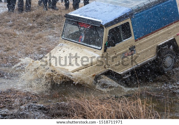 Taraclia, Moldova - 23. 02. 2019: Rally on Russian\
SUVs in the mud in winter, Trapped all-terrain vehicle pulled out\
of the river