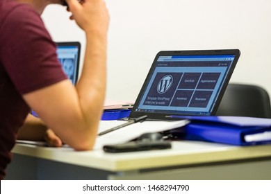 Taranto, Italy - July 19, 2019: Young student follows the lesson with a laptop in front of him with the Wordpress logo on the display.