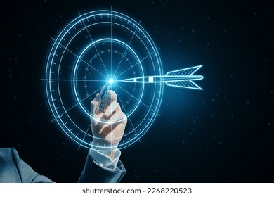Target concept with a glowing hologram of bullseye and arrow hitting the center. Growth strategy. Goals achievement, success. Close up of businessman hand using hud screen on blurry dark background