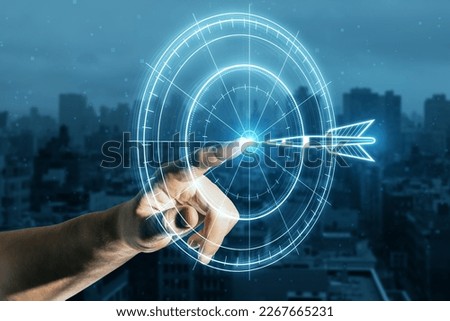 Target concept with a glowing hologram of bullseye and arrow hitting the center. Growth strategy. Close up of male hand using hud screen on blurry city backdrop. Double exposure
