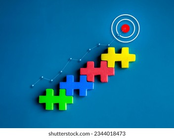 Target icon on top of colorful puzzle blocks as a bar graph chart steps with rise up finance line chart on blue background. Business growth process, profit, investment, economic improvement concepts. - Powered by Shutterstock