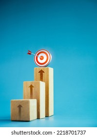 Target icon on top of wooden blocks with rise up arrows, 3d bar graph chart steps on blue background, vertical style, business growth process, profit, investment, economic improvement concepts. - Shutterstock ID 2218701737