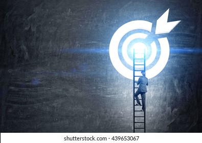 Targeting concept with businessman climbing ladder to abstract illuminated dartboard sketch on chalkboard - Shutterstock ID 439653067