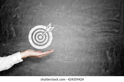 Targeting concept with businessman hand holding dartboard sketch on chalkboard - Powered by Shutterstock