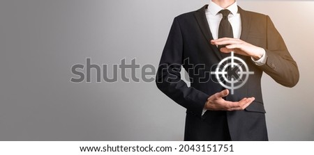 Targeting concept with businessman hand holding target icon dartboard sketch on chalkboard. Objective target and investment goal concept