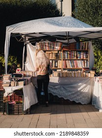 TARGU MUR, ROMANIA - Jul 21, 2022: A Blonde Woman Buys Books From A Temporary Book Store Tent In The City Center  There Was An Event For Old Second-hand Books 