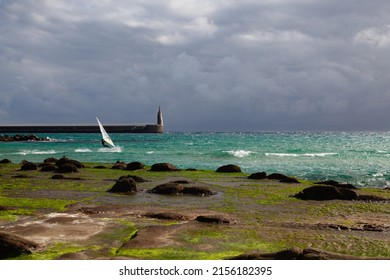 Tarifa, Spain - February 6,2022: Wind Surfer on the beach in Tarifa. Lighthouse in Tarifa and dramatic sky, Andalusia, Spain.Tarifa is one of the world's most popular destinations for windsports