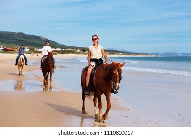 TARIFA, SPAIN - MAY 6, 2018:People horse riding on the beach. Sport, leisure and travel concepts