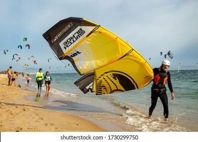 TARIFA, SPAINE - July 19, 2018: Tarifa, Spain: Kitesurfer going along beach  doing sports in the Atlantic ocean. Beautiful white Tarifa beach packed with kitesurfers and sunbathers. 