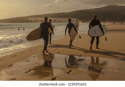 Tarifa, Spain;September 19 2020:Surfers walk the beach at sunset looking for good waves to surf