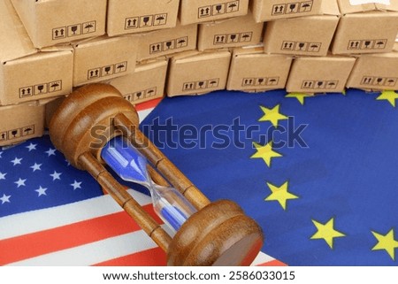 Tariffs and trading ruses changing between EU and USA. European Union and US flags with many carton boxes and hourglass.	