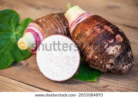 Taro root with half slice on taro leaf and wooden background, Fresh raw organic taro root ready to cook
