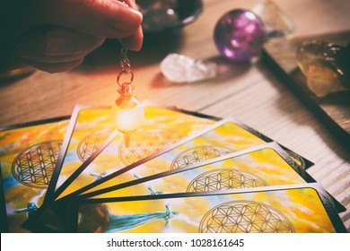 Tarot cards dowsing tool in hand and crystals as a concept of psychic advisor or ways of divination