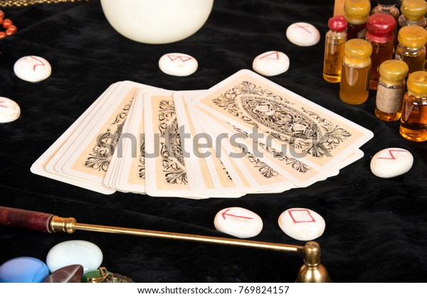 Tarot cards with runes and magical attributes on\
the table