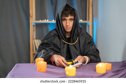 Tarot reader picking tarot cards near burning candles.Candlelight in dark.Tarot reader or fortune teller reading and forecasting concept. Copy space - Shutterstock ID 2228465925