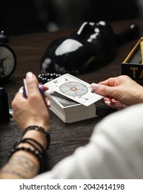 Tarot Reader Picking Tarot Cards.Tarot Cards Face Down On Table And One Card Is Face Up. Black Masks Are On The Background.Tarrot Reader Or Fortune Teller Reading And Forecasting Concept.