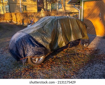 Tarp Covered Car In Front Of Yellow House And Garage 