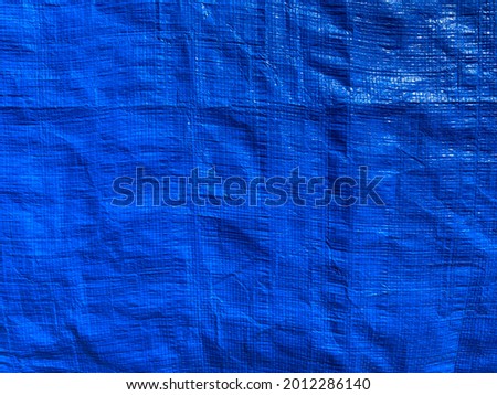 Tarpaulin, crumpled blue tarp. Background of strong, flexible, waterproof material. Canvas or polyester coated with polyurethane. Polyethylene, plastics.