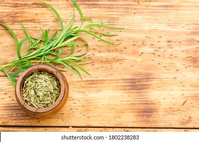 Tarragon or estragon.Artemisia dracunculus.Fresh and dry tarragon herb on wooden table.Space for text