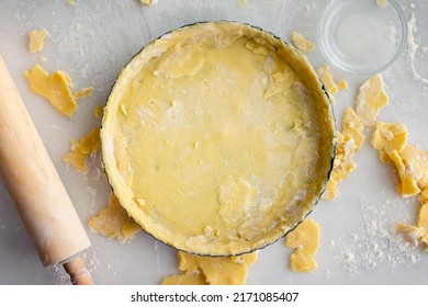 Tart Pan Filled with Raw Pastry Dough: Uncooked pie crust in a tart pan shown with a rolling pin