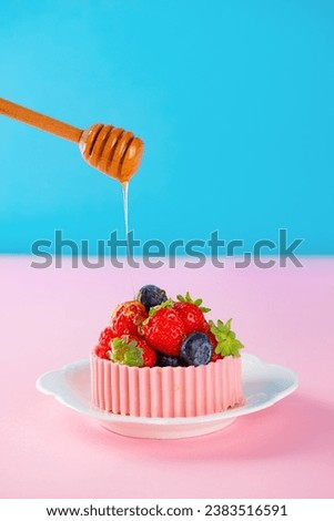 Tartlet with berries and a basket of pink chocolate with honey in a plate. Cake baskets with delicate cream and berries. Vertical orientation.