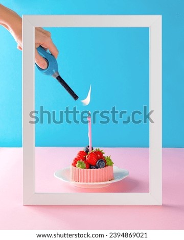 Tartlet with berries and a basket of pink chocolate with a candle lit by a lighter in a frame. Cake baskets with cream and berries. Vertical orientation.