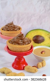 Tartlets With Avocado, Peanut Butter Mousse And Chocolate On White Background