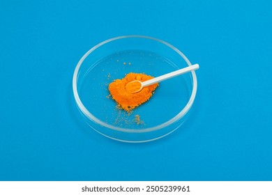 Tartrazine powder in Petri dish with measuring spoon. Synthetic lemon yellow azo dye. Food additive E102. Tartrazine, usually labelled as CI 19140 or FDC Yellow 5.
