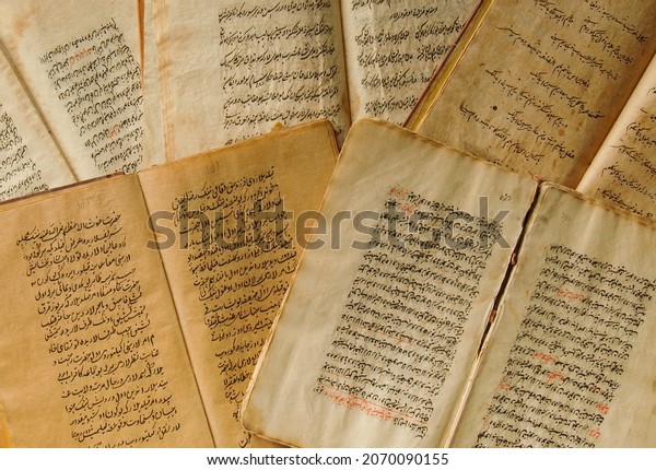 Tashkent, Uzbekistan - August 10, 2009: Stack of\
open ancient books in Arabic. Old Arabic manuscripts and texts. Top\
view