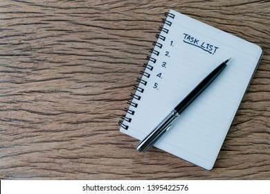 Task checklist in project management concept, pen on white paper notepad with handwritten headline as Task List and numbers listed on wood table, writing business project with tasks prioritize. - Shutterstock ID 1395422576
