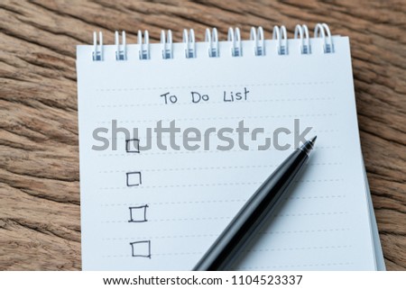 Task checkmark, To Do List checkbox written with pen on white paper notepad on wood table in soft tone, writing business project with tasks priority concept.