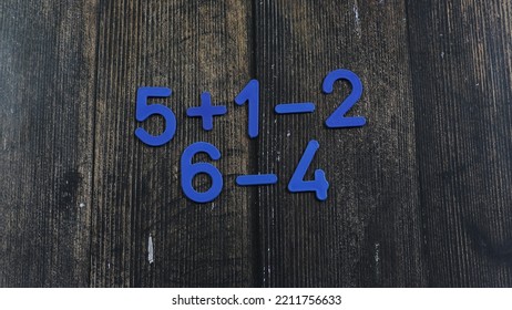 Task In Mathematics. Mathematics Problem For Children. Simple Algebra Examples Using Numbers And Signs From Plastic Numbers On A Wooden Background.