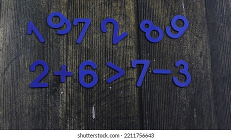 Task In Mathematics. Mathematics Problem For Children. Simple Algebra Examples Using Numbers And Signs From Plastic Numbers On A Wooden Background.