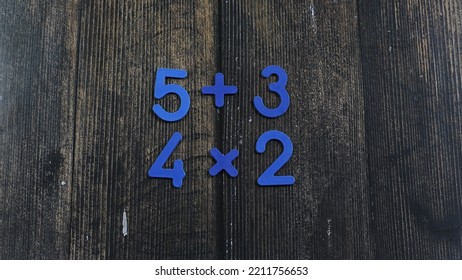 Task In Mathematics. Mathematics Problem For Children. Simple Algebra Examples Using Numbers And Signs From Plastic Numbers On A Wooden Background.