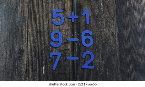 Task In Mathematics. Mathematics Problem For Children. Simple Algebra Examples Using Numbers And Signs From Plastic Numbers On A Wooden Background.