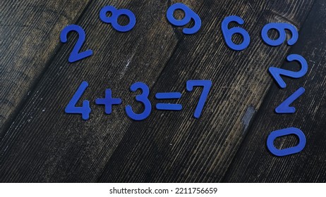 Task In Mathematics. Mathematics Problem For Children. Simple Algebra Examples Using Numbers And Signs From Plastic Numbers On A Wooden Background.