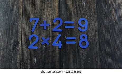 Task In Mathematics. Mathematics Problem For Children. Simple Algebra Examples Using Numbers And Signs From Plastic Numbers On A Wooden Background.