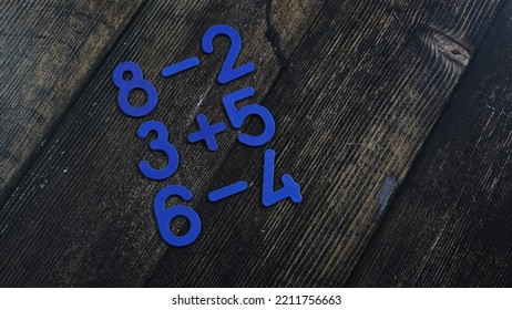 Task In Mathematics. Mathematics Problem For Children. Simple Algebra Examples Using Numbers And Signs From Plastic Numbers On A Wooden Background.