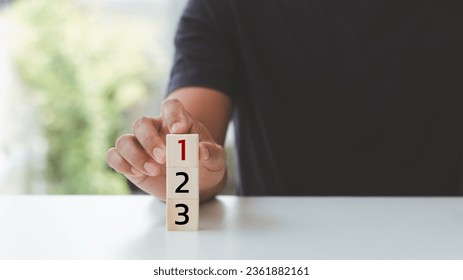 Task priority and management concept. The order of priority in any activity. Set work priorities, and arrange a to-do list. Hand arranging wooden cubes with numbers first, second, and third.