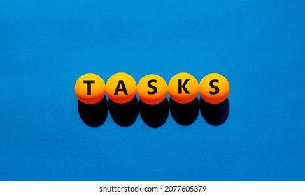 Tasks symbol. The concept word 'tasks' on orange table tennis balls. Beautiful blue table, blue background. Business and task or tasks concept.